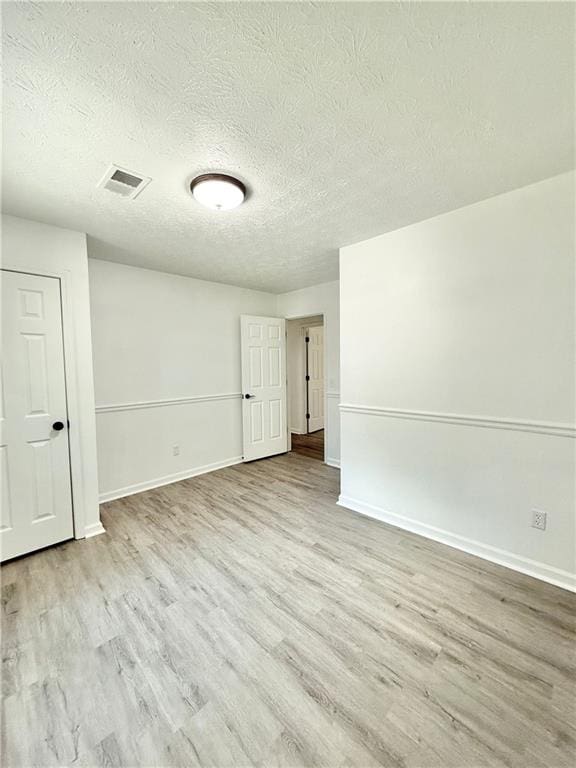 spare room featuring a textured ceiling, baseboards, and wood finished floors