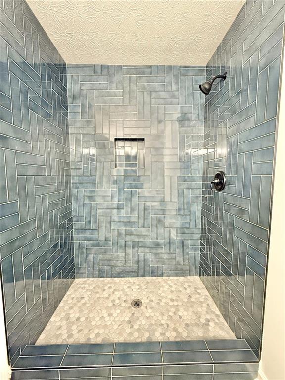 bathroom with tile patterned floors and a tile shower