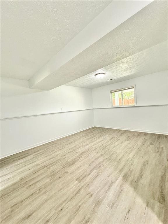 additional living space with a textured ceiling, wood finished floors, and baseboards