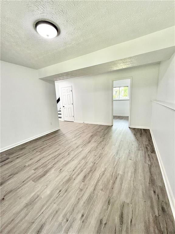 below grade area featuring a textured ceiling, wood finished floors, and baseboards