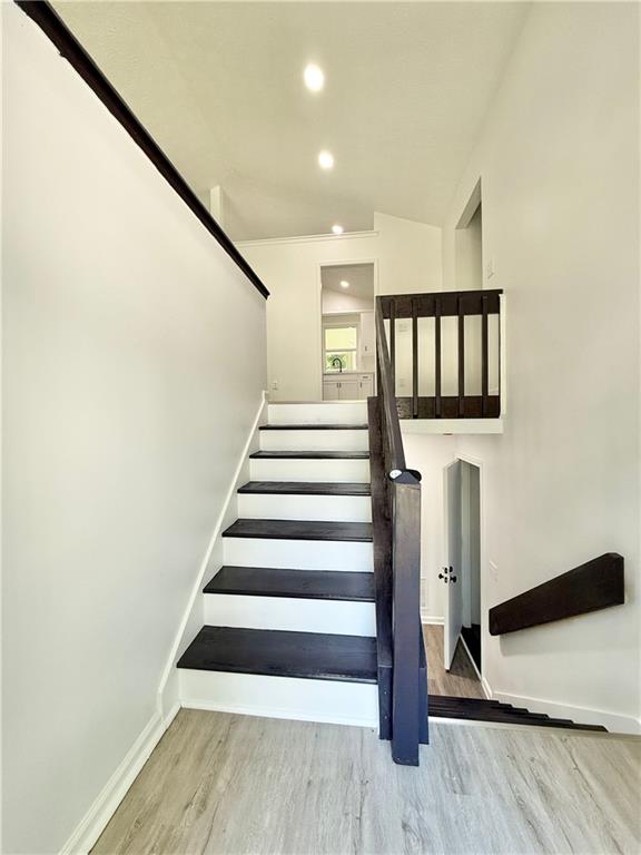 stairs with baseboards, lofted ceiling, recessed lighting, and wood finished floors