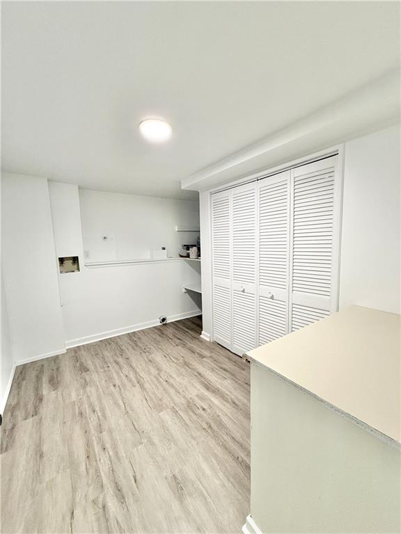 washroom featuring laundry area, light wood-type flooring, and baseboards