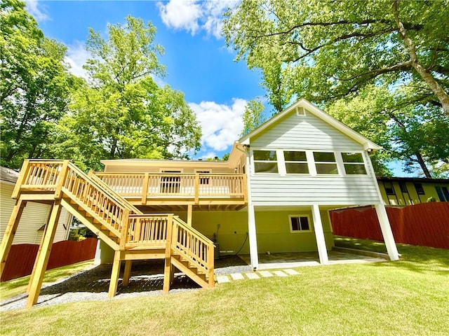 rear view of property featuring a lawn, stairway, fence, and a wooden deck