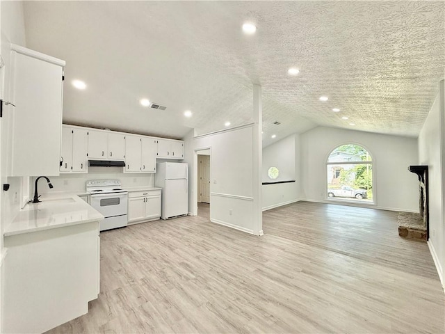 kitchen with a sink, white appliances, under cabinet range hood, open floor plan, and light countertops