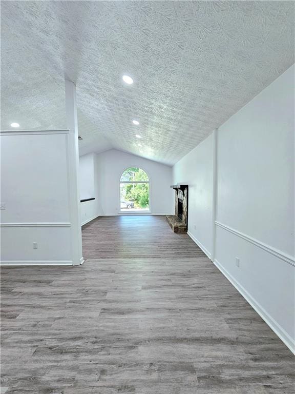unfurnished living room with lofted ceiling, a textured ceiling, and wood finished floors