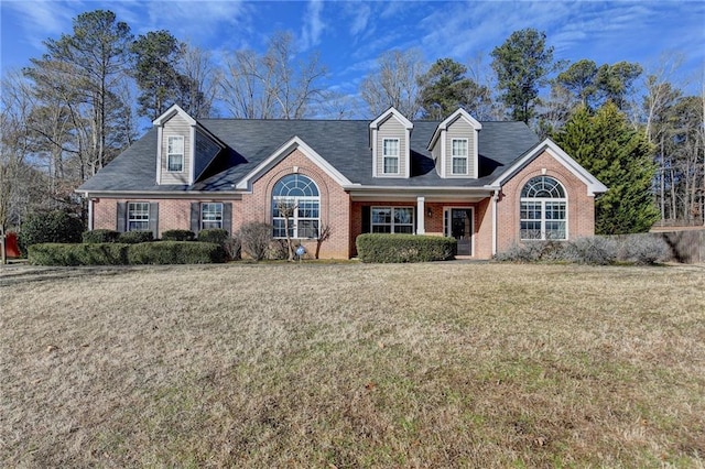 cape cod home with brick siding and a front yard