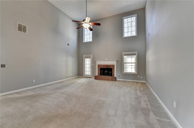 unfurnished living room with a fireplace, carpet flooring, visible vents, baseboards, and a ceiling fan