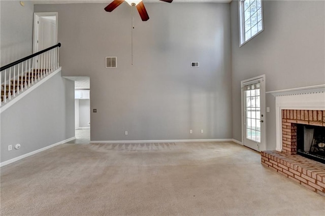 unfurnished living room featuring a wealth of natural light, carpet, and a brick fireplace