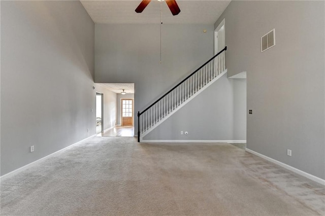 unfurnished living room featuring visible vents, baseboards, ceiling fan, stairway, and carpet floors