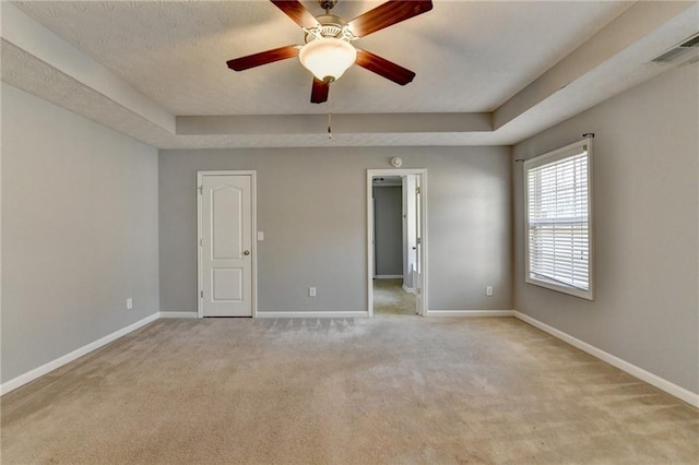 unfurnished room with a raised ceiling, visible vents, and baseboards