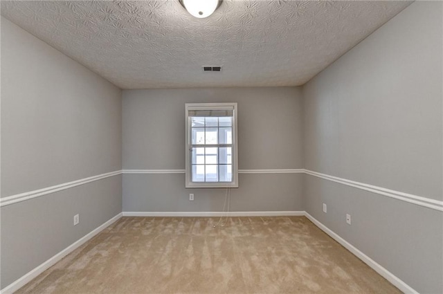 unfurnished room with carpet floors, baseboards, visible vents, and a textured ceiling