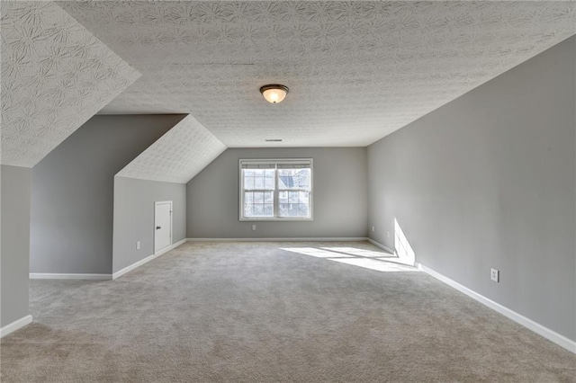 additional living space with a textured ceiling, carpet floors, and baseboards