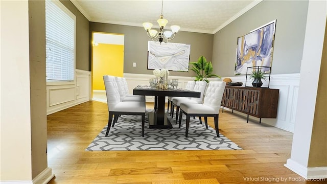 dining room featuring wainscoting, an inviting chandelier, wood finished floors, and crown molding