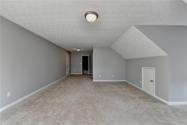 additional living space with lofted ceiling, baseboards, a textured ceiling, and carpet flooring