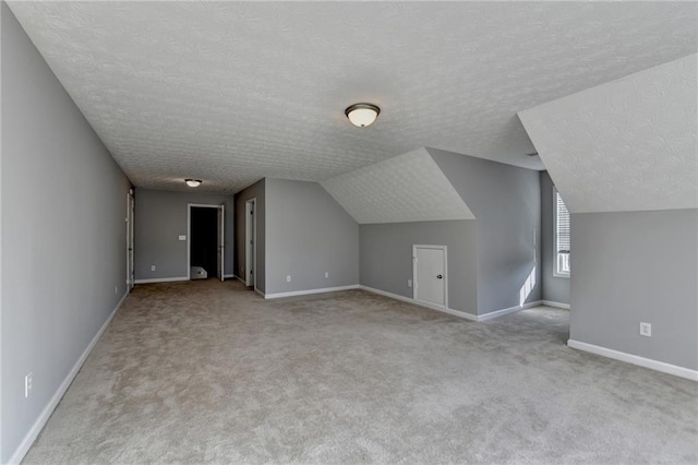 bonus room featuring carpet, baseboards, vaulted ceiling, and a textured ceiling