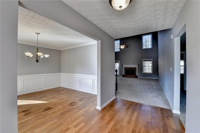 interior space with baseboards, wainscoting, wood finished floors, a textured ceiling, and a fireplace