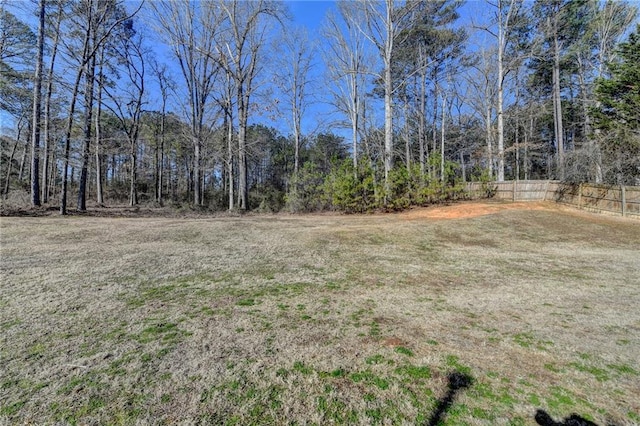 view of yard with a forest view and fence