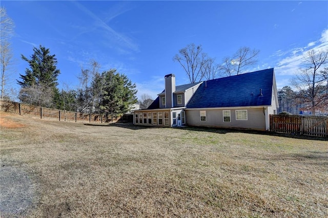 back of property featuring a shingled roof, a fenced backyard, a yard, and a chimney