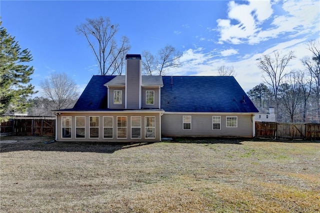 rear view of property with a sunroom, a chimney, fence, and a yard