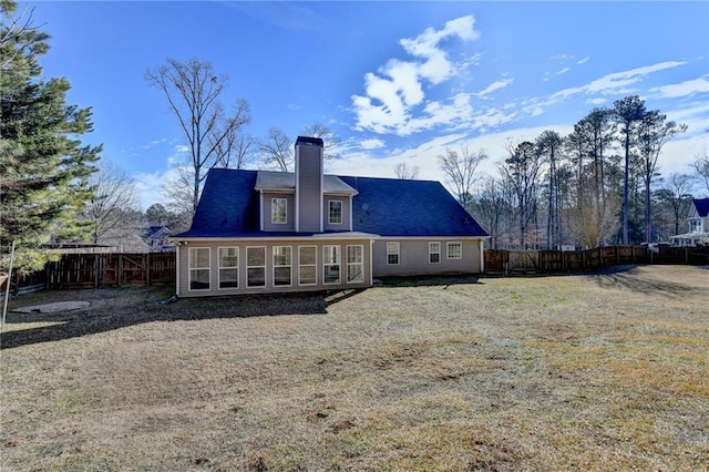 back of house with a chimney, a fenced backyard, and a sunroom