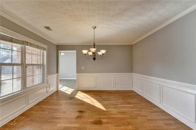 unfurnished dining area with a chandelier, a textured ceiling, visible vents, and light wood-style floors