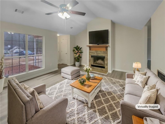 living area featuring vaulted ceiling, light wood-style flooring, a fireplace, and visible vents