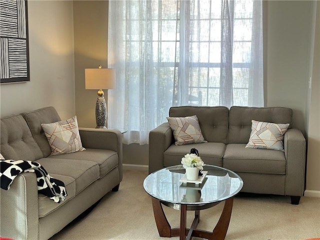 living room featuring baseboards, a wealth of natural light, and light colored carpet