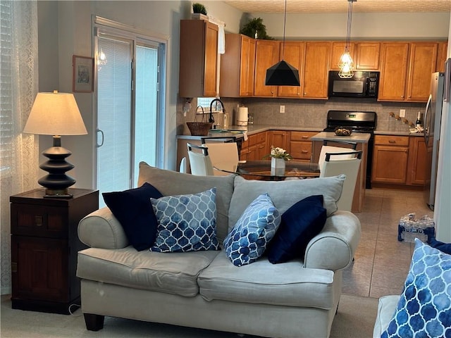 kitchen featuring hanging light fixtures, appliances with stainless steel finishes, brown cabinetry, and a sink