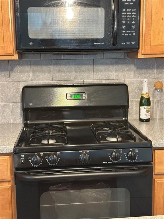 kitchen with brown cabinets, black appliances, light countertops, and decorative backsplash