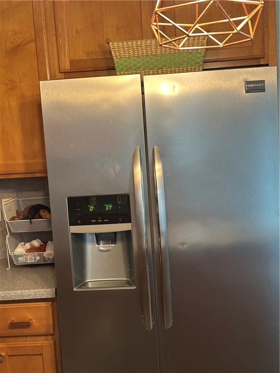 room details featuring brown cabinets and stainless steel fridge with ice dispenser