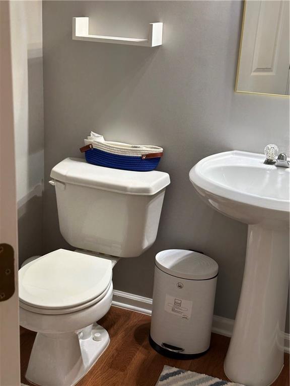 bathroom featuring baseboards, a sink, toilet, and wood finished floors