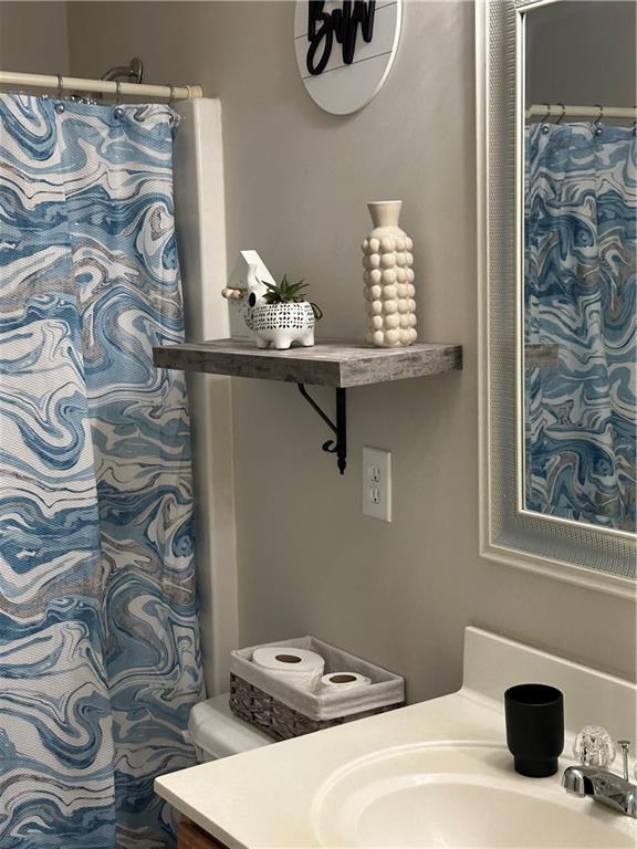 full bath with a shower with shower curtain, toilet, and vanity