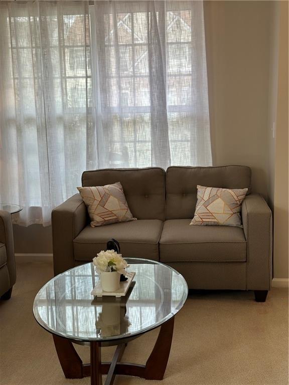 living area with baseboards and light colored carpet