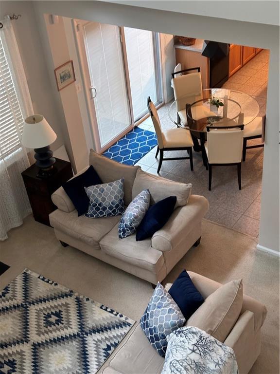 living area with light tile patterned floors, plenty of natural light, and light carpet