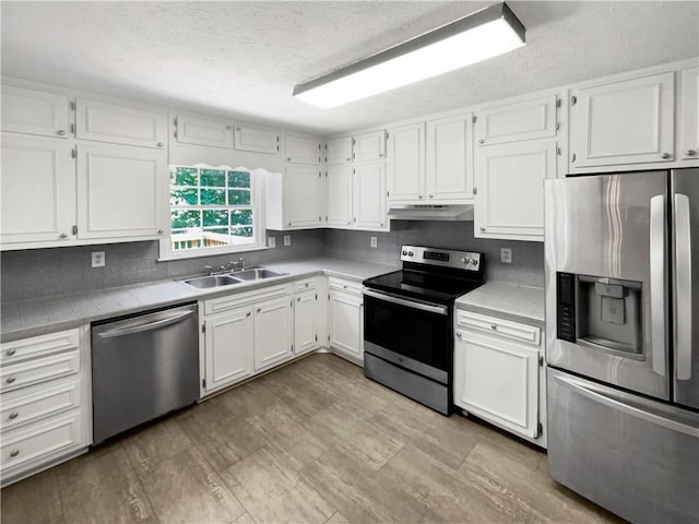 kitchen with stainless steel appliances, white cabinets, and sink