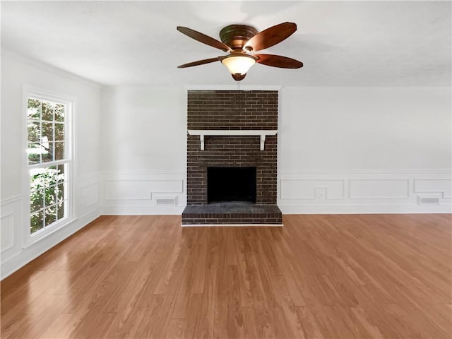 unfurnished living room with a fireplace, ceiling fan, and light hardwood / wood-style floors