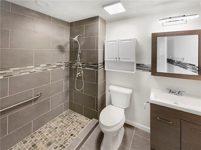 bathroom featuring tile patterned flooring, a tile shower, vanity, and toilet