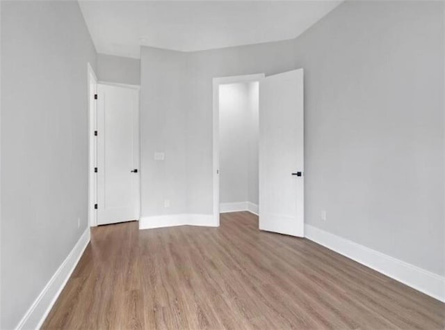 spare room featuring baseboards and wood finished floors