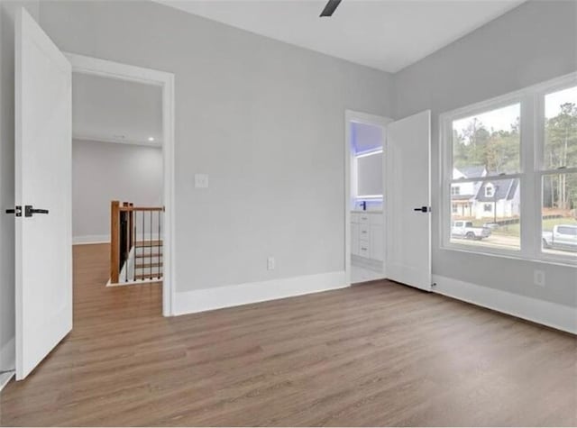 spare room with baseboards, ceiling fan, and wood finished floors