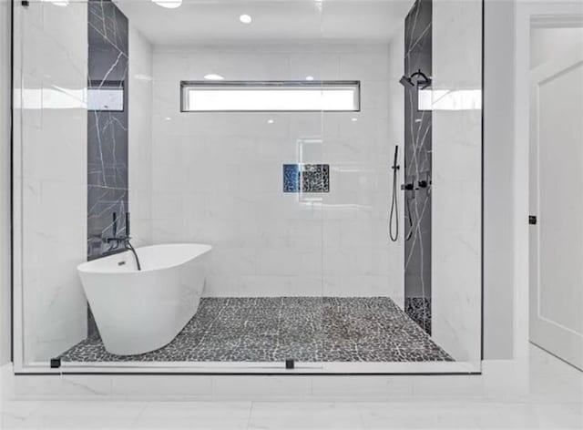 bathroom featuring a marble finish shower and a freestanding bath