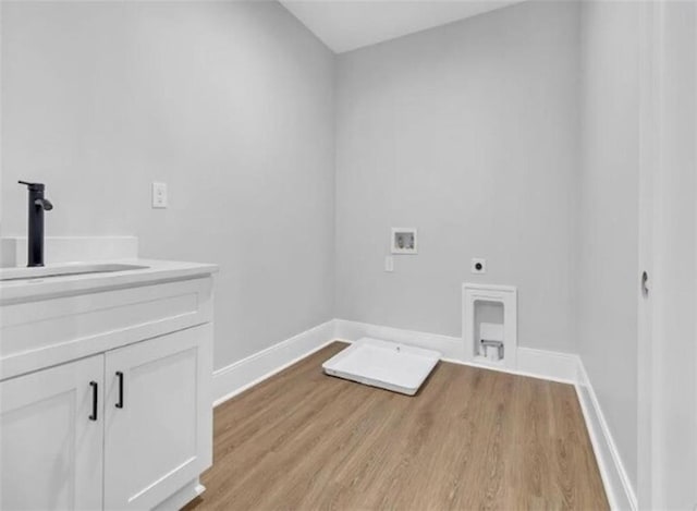 clothes washing area featuring cabinet space, washer hookup, a sink, light wood finished floors, and hookup for an electric dryer