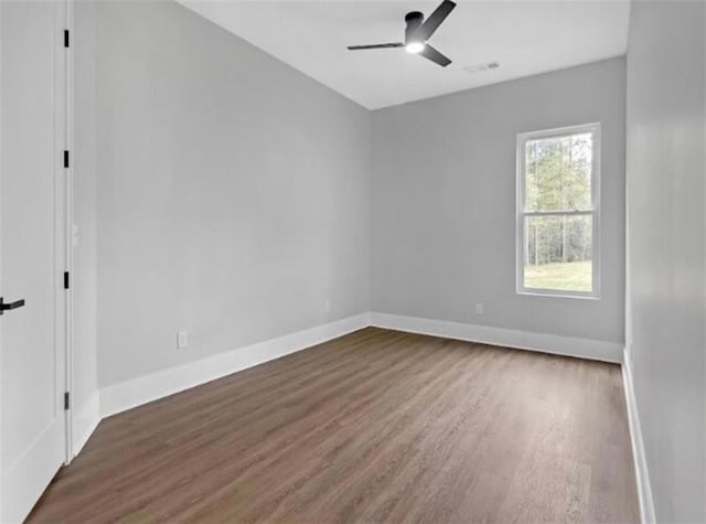 spare room with baseboards, ceiling fan, and wood finished floors