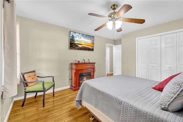 288 Valerie Cir, Hiram, GA 30141 - bedroom with a closet, light wood-style flooring, a glass covered fireplace, and a ceiling fan