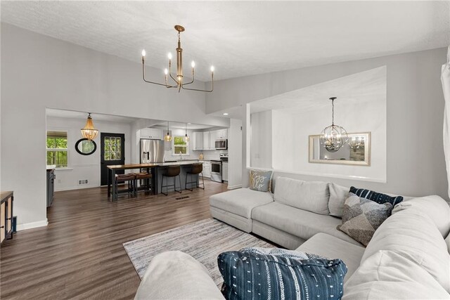 living room with dark wood-style flooring, baseboards, and a notable chandelier