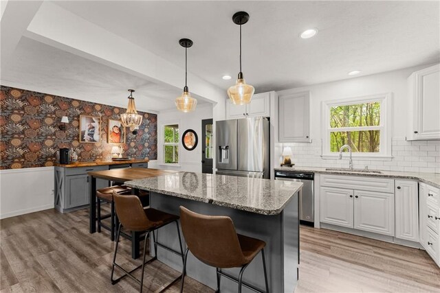kitchen with stainless steel appliances, light wood-style flooring, a sink, and a kitchen island