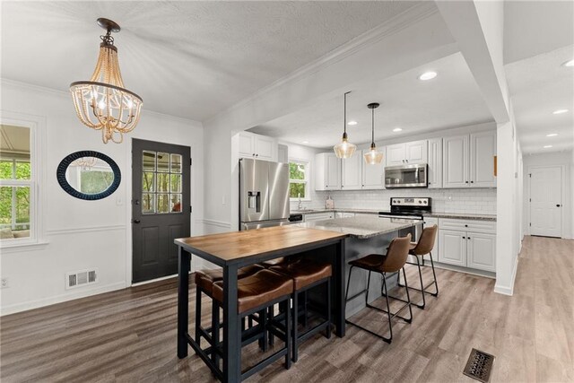 dining room with light wood-style floors, a notable chandelier, visible vents, and recessed lighting