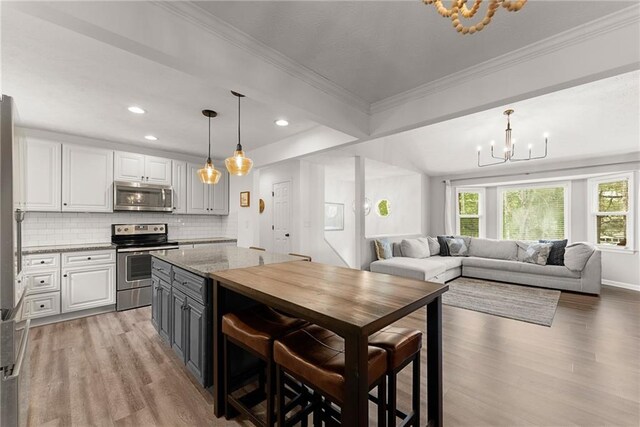 kitchen with open floor plan, appliances with stainless steel finishes, a chandelier, and light wood-style floors