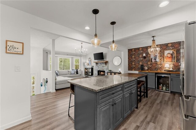 kitchen with a notable chandelier, freestanding refrigerator, a kitchen breakfast bar, and beverage cooler