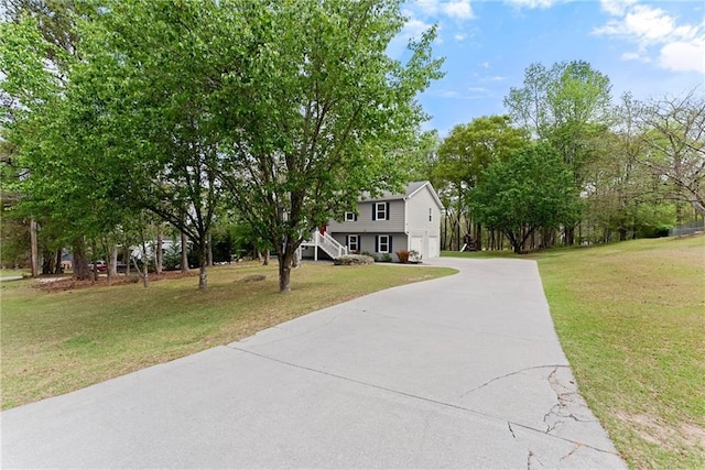 view of front facade with a garage, stairs, a front lawn, and concrete driveway