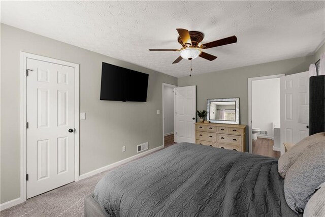 bedroom featuring visible vents, baseboards, ensuite bathroom, and a textured ceiling